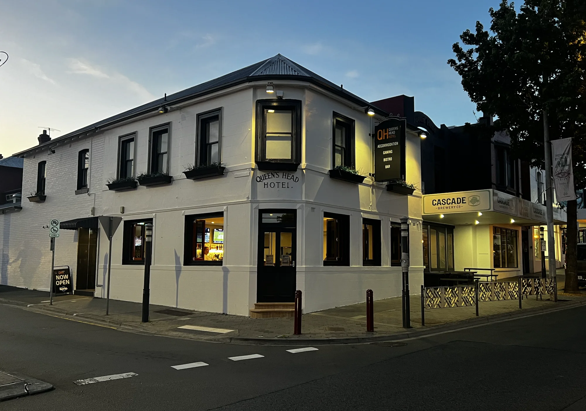 The illuminated heritage facade of the Queen’s Head Hotel at dusk